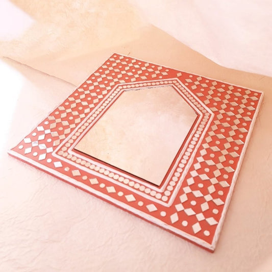 Bright brick red handcrafted mud art mirror, adding warmth and character