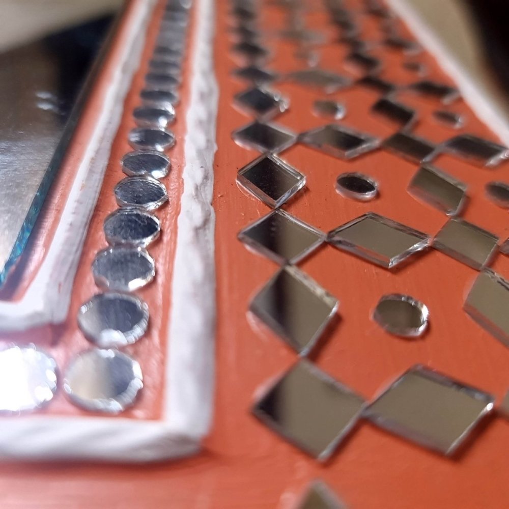Artisanal bright brick red handcrafted mud art mirror, showcasing traditional craftsmanship 